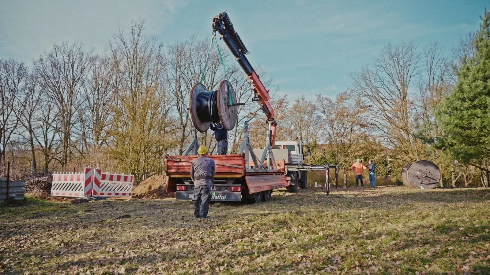 Ladekran hebt eine Kabeltrommel auf einer Baustelle