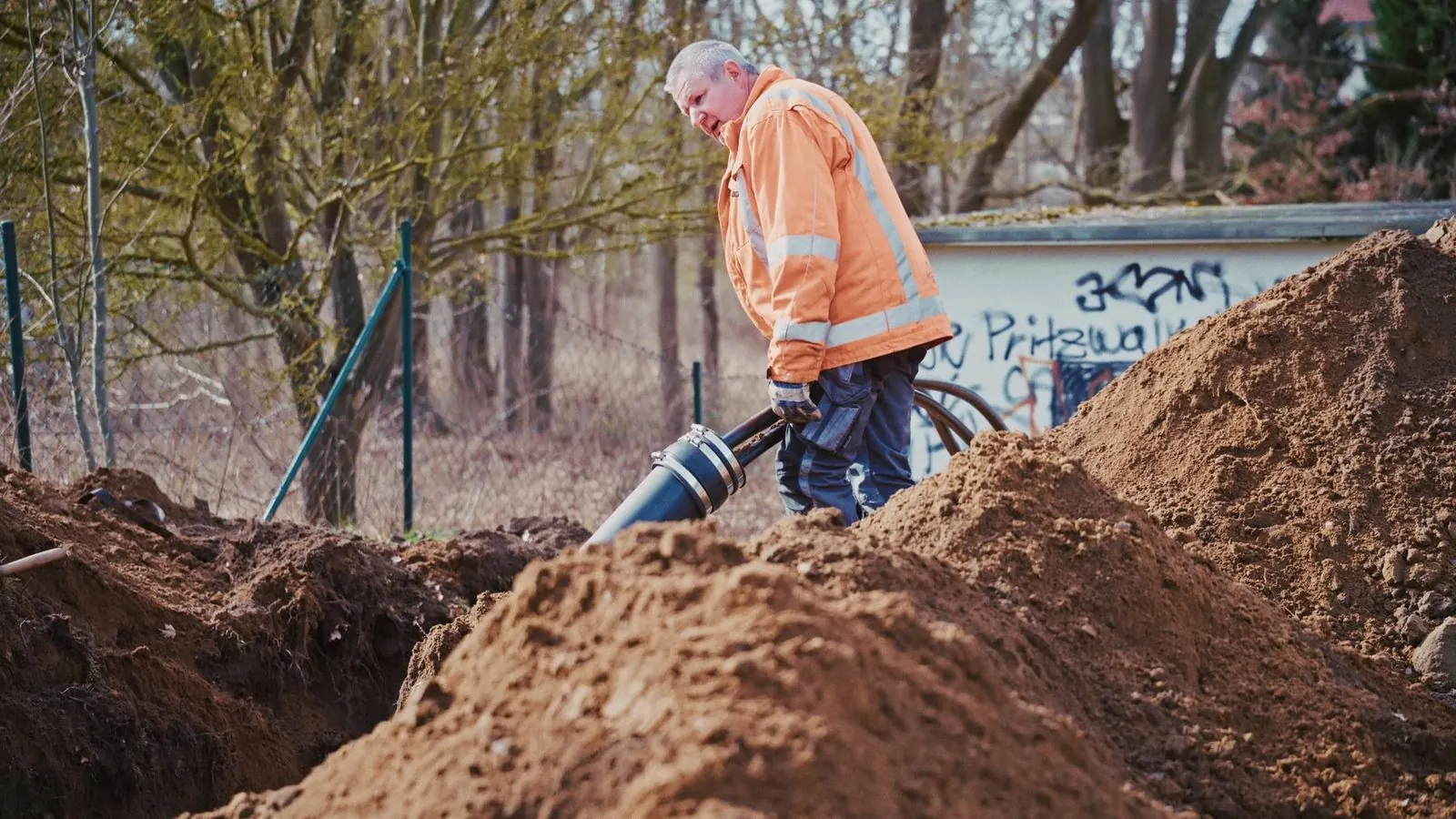 Tiefbauer legt ein Rohr in den Graben